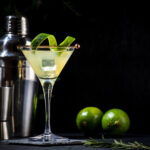 Classic alcoholic cocktail with vodka, syrup, lime, juice and ice in martini glass, dark background