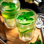 Mojito with pieces of lime and mint leaves. On a black background. High quality photo